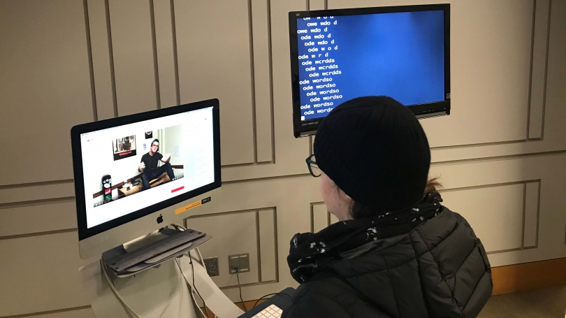 A person sitting in front of two computer screens. 